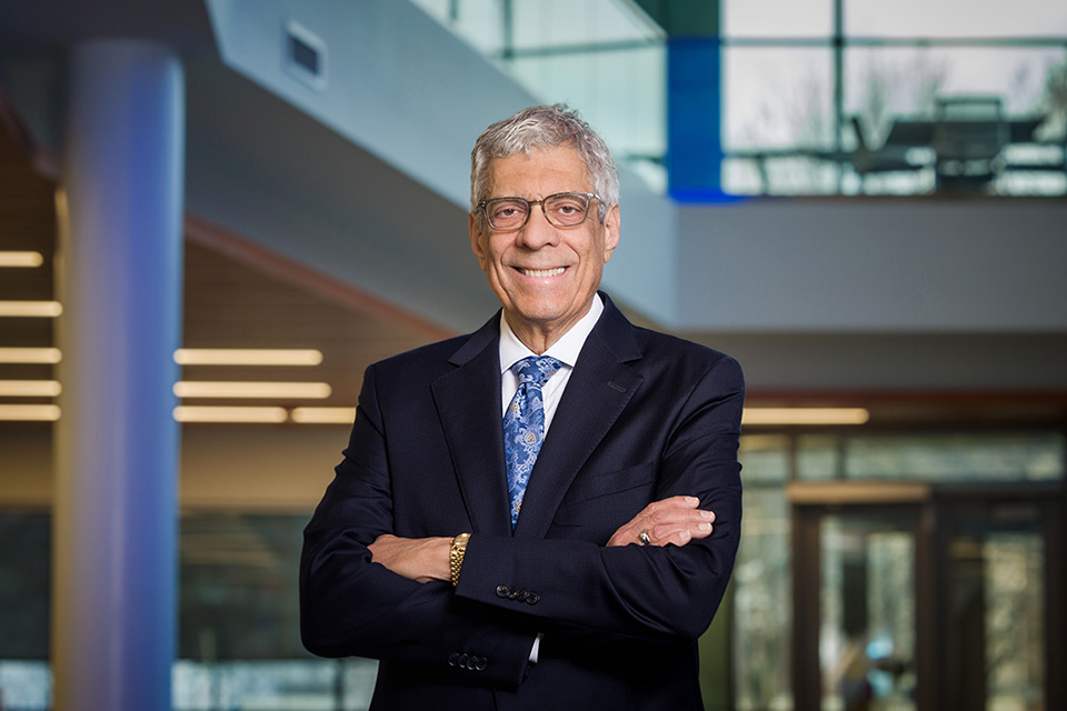 SLU President Dr. Fred Pestello wearing glasses, a suit and tie standing in the atrium of SLU's Interdisciplinary Science and Engineering Building